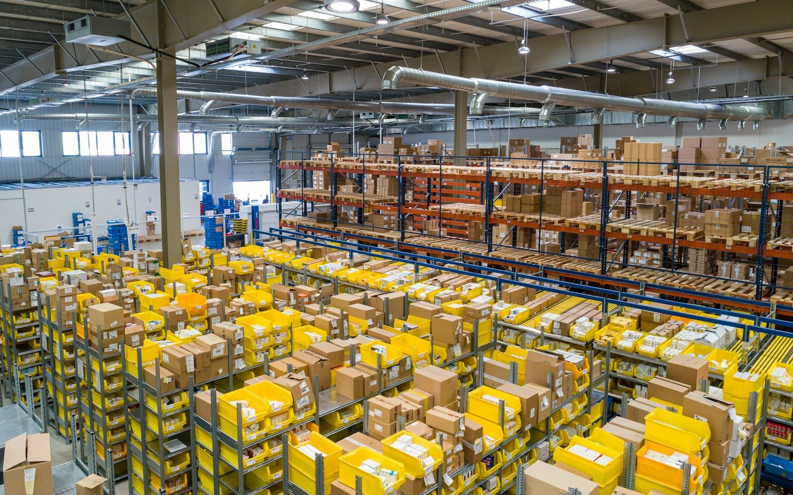 A warehouse interior with rows of pallets and labelled packages on racks